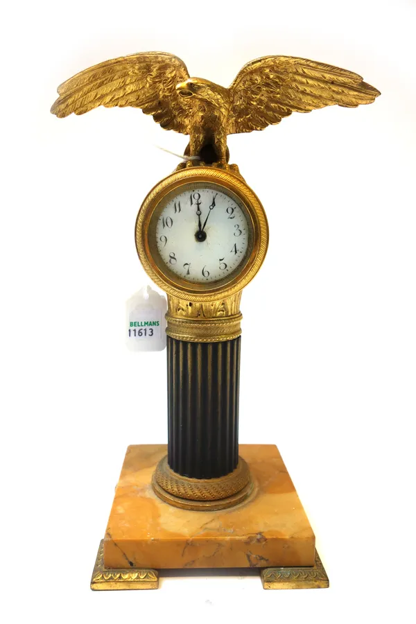 A French gilt and ebonised metal mantel clock, 19th century, surmounted by an outstretched eagle over a white enamel dial, fluted column and Siena mar