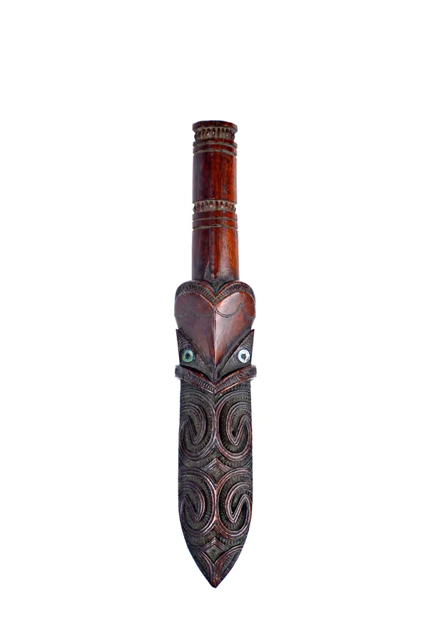A Maori 'Taiaha', 19th century (lacking shaft), the spear form head with symmetrical carving, with inset mother-of-pearl decoration.  Illustrated
