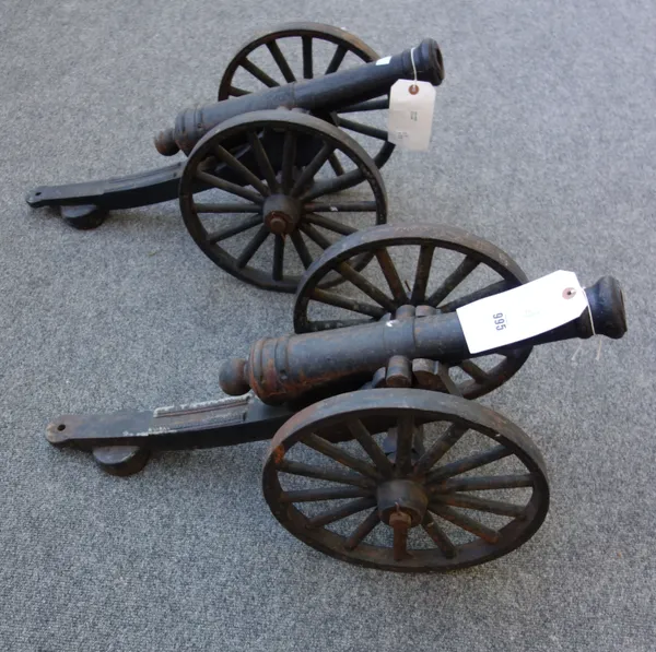 A pair of modern cast iron cannons, each circular tapering barrel on a carriage and spoked wheels, the barrel 44.5cm long, (2).