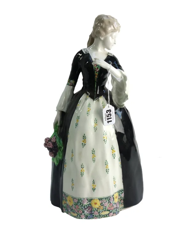 A Goldschieder pottery figure of a Victorian lady, circa 1900, modelled wearing a white foliate decorated dress and black cape, impressed and printed