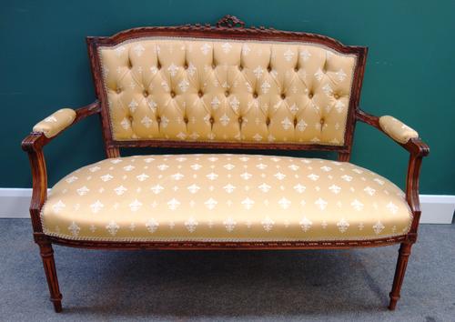 A Louis XVI style walnut framed open arm sofa, on fluted supports, 124cm wide x 93cm high.