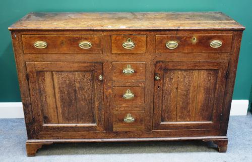 A George III oak dresser base, with three drawers over cupboards, on bracket feet, 140cm wide x 91m high.
