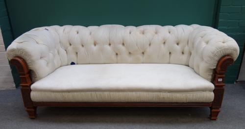 Maple & Co; a mid Victorian walnut frame Chesterfield sofa, the roll over arms with floral carved shaped frame, on tapering square supports, the back