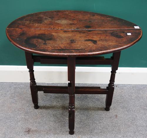 A 17th century oak coaching table, with oval top and folding turned base, 53cm wide x 68cm long.