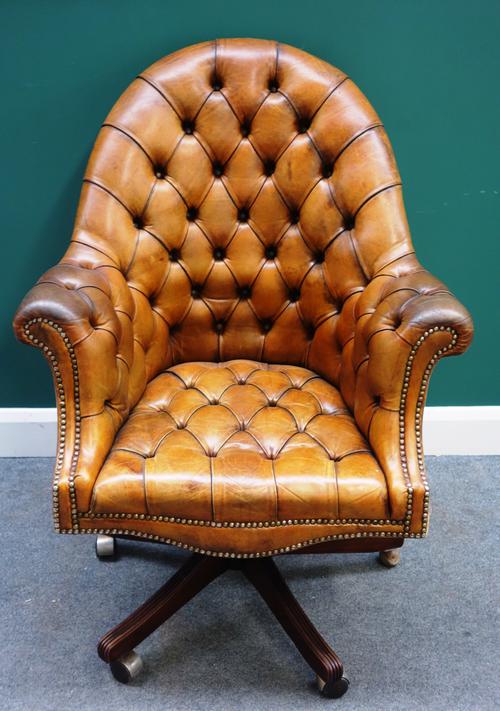 A 20th century studded brown leather office tub back swivel chair, on a five point base, 80cm wide x 113cm high.