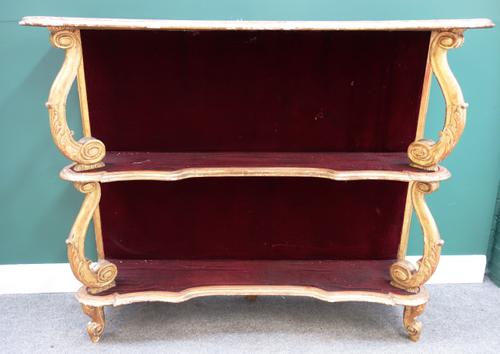 A mid-19th century French gilt framed floor standing set of open shelves, with three serpentine tiers, on scroll supports, 150cm wide.