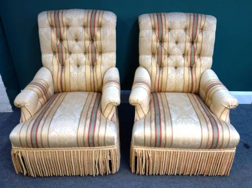 A pair of 20th century button back easy armchairs, each with straight front seat and tassel frieze, on turned stained beech supports, 66cm wide x 96cm