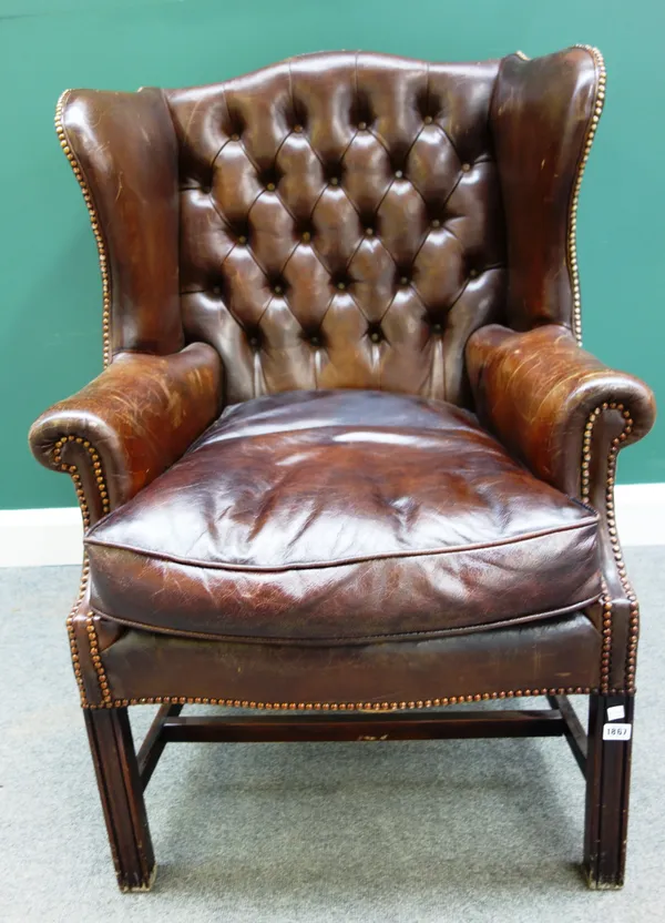 An 18th century style brown leather upholstered wingback armchair, on block supports, 80cm wide x 111cm high.