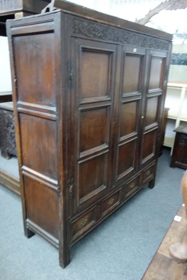 An 18th century oak nine panel hall cupboard, with two drawer base, carved 'PHI 1698', 173cm wide x 188cm high.