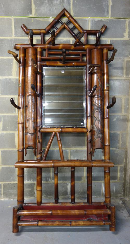 An early 20th century split bamboo mirror back coat/umbrella stand, 122cm wide x 247cm high.,
