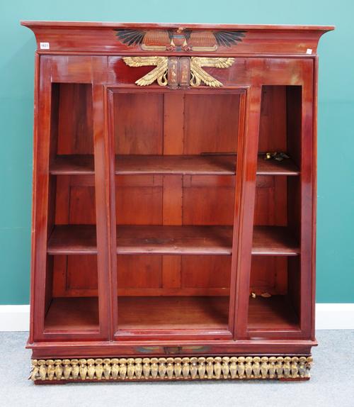A 20th century parcel gilt Egyptian Revival open bookcase of tapering form, 127cm wide x 156cm high.