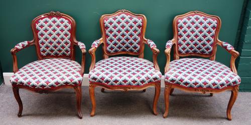 A matched set of three walnut framed Louis XV open arm fauteuils, on scroll supports, each 65cm wide x 88cm high (3).