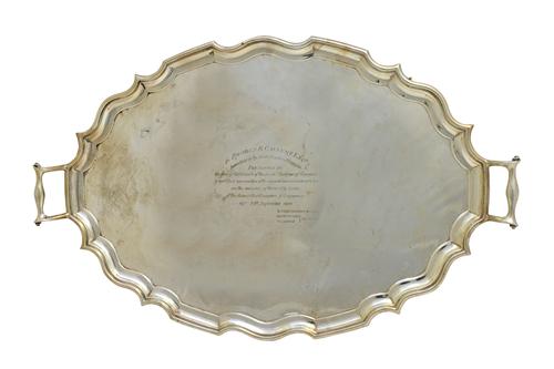 A silver shaped oval twin handled tray, having a pie-crust rim and raised on four scrolling feet, in the 18th century taste, London 1910, presentation