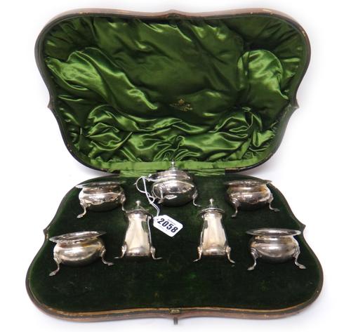 A silver seven piece condiment set, comprising; four salts (lacking liners), two pepperettes and a mustard pot with a blue glass liner, Birmingham 190