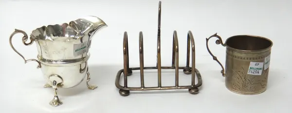 A silver five bar toastrack, having a loop shaped handle, raised on four bun feet, London 1902, a silver helmet shaped milk jug, with a scrolling hand