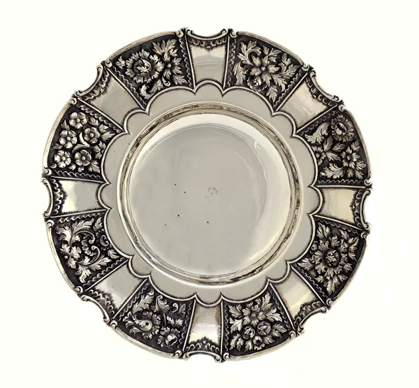 A Greek shaped circular silver bowl, decorated with floral and foliate panels within arcaded borders, raised on three cast, scroll pierced feet, prese