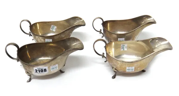 A set of four silver sauceboats, each with a scrolling handle, decorated rim and raised on three feet, Sheffield 1927, combined weight 785 gms.