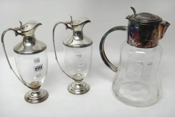 A pair of silver mounted glass claret jugs, each or urn shaped form, the rims and the handles with beaded decoration, height 27cm and a silver plated