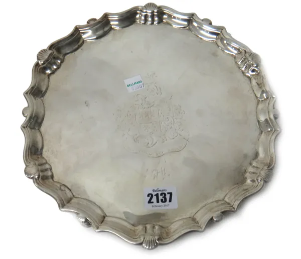 A George II silver salver, of shaped circular form, having a pie-crust rim and raised on three pad feet, engraved to the centre with a shield, crest,