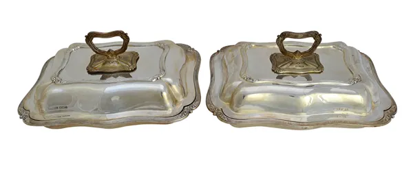 A pair of silver shaped rectangular lidded entree dishes, each decorated with reeded borders and with foliate motifs to the corners, with detachable h