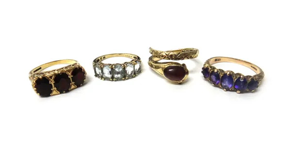 A 9ct gold and carbuncle garnet set ring, designed as a coiled snake, a 9ct gold and amethyst set five stone ring, a 9ct gold and pale blue gem set fi