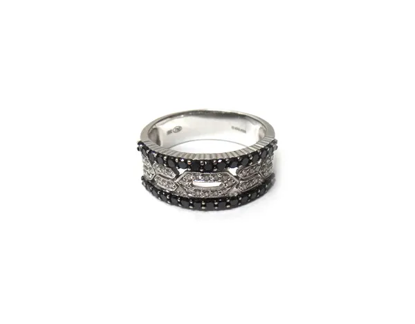 A white gold, diamond and black diamond set ring, the centre in a pierced geometric design, mounted with circular cut diamonds, the sides mounted with