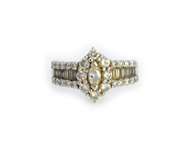 A diamond ring, the centre mounted with a marquise shaped diamond, in a surround of eight circular cut diamonds, the shoulders mounted with a central