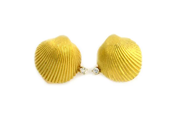 A pair of gold and diamond set earclips, each designed as a scallop shell, claw set with a circular cut diamond, detailed 18 K and with a clip fitting