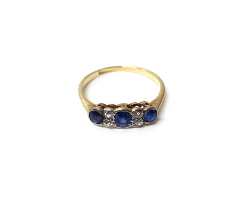 A gold and platinum, diamond and sapphire set ring, mounted with three cushion shaped sapphires and with two pairs of cushion shaped diamonds, mounted