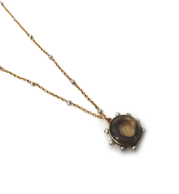 A late Victorian Child & Child gold and seed pearl set circular pendant locket, glazed to the front with a hairwork spray, the back inscribed and deta