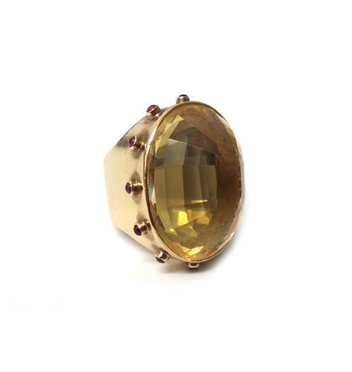 A 9ct gold ring, mounted with an oval cut large citrine to the centre, within a surround of cabochon rubies, in a Game of Thrones design, ring size O