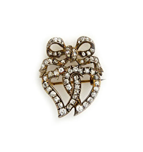 A diamond brooch, designed as two entwined hearts, with a ribbon tied bow surmount, mounted with cushion shaped and rose cut diamonds, in the late 19t