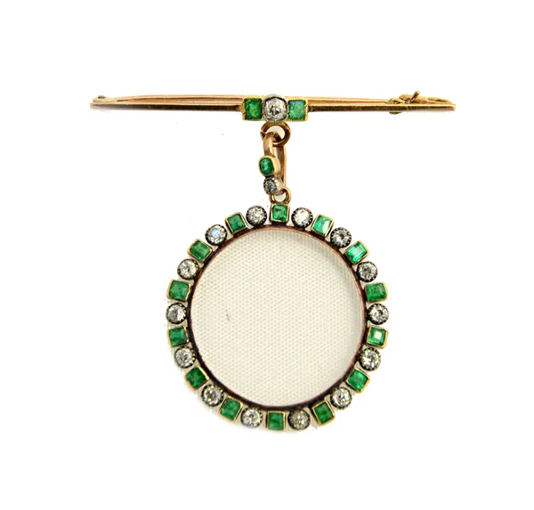 A diamond and emerald circular pendant frame mounted with alternating cushion shaped diamonds and cushion shaped emeralds, within square shaped settin