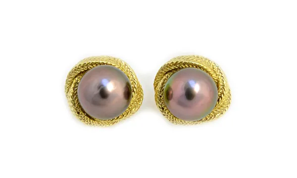 A pair of gold and black tinted cultured pearl earclips, each mounted with a large black tinted cultured pearl, within a cast ropetwist surround, the