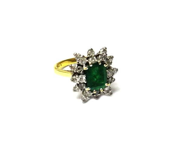 An 18ct gold, emerald and diamond set cluster ring, claw set with the cut cornered rectangular step cut emerald at the centre, within a radiating surr