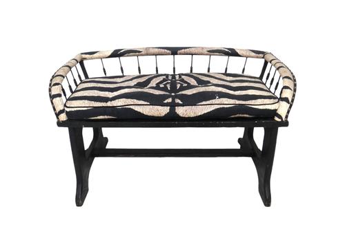 A faux zebra skin upholstered two seat bench, with splayed spindle back on dual standard ends, 105cm wide. K3Provenance- from the estate of Fleur Cowl