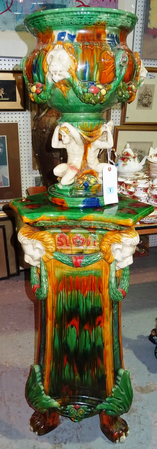A large 20th century majolica style ceramic jardiniere and stand, the jardiniere with lion mask decoration supported by three crouching men, overall h