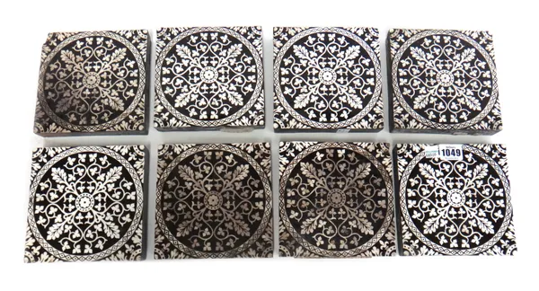 Eight Minton & Co Arts and Crafts tiles, each foliate decorated in white against a black ground, stamped to the rear 'Minton & Co Patent, Stoke Upon T