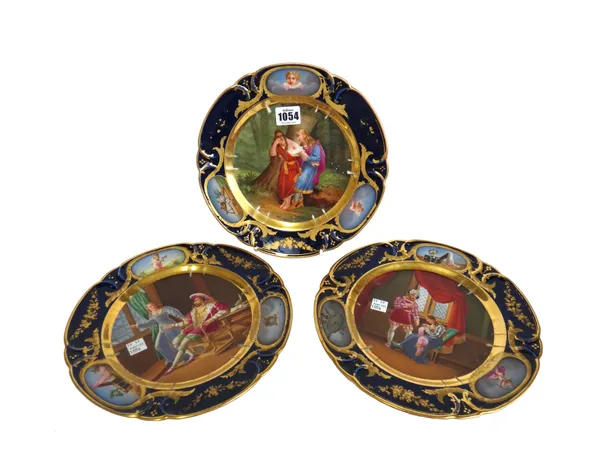 Three French cabinet plates, 19th century, each decorated with classical figures, within a wide gilt foliate and cobalt blue shaped border, titled to