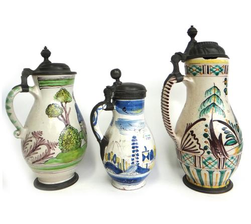 Three Continental faience tankards, probably Gmunden, Austria, late 18th/19th century, each with a pewter hinged lid, decorated with figures, flowers