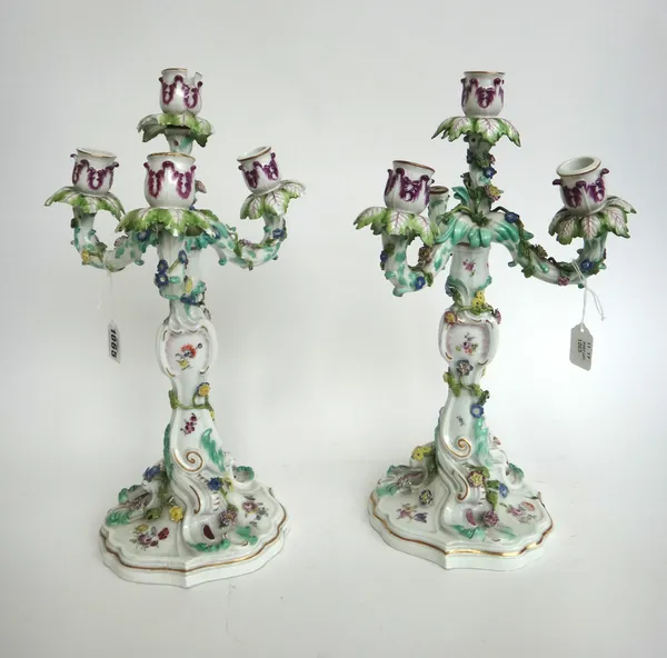 A pair of Meissen four branch candelabra, circa 1760, blue crossed swords mark, decorated with trailing foliate vines over a shaped foot, (a.f), 39cm