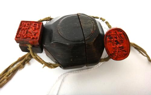 A Chinese rhino horn portable seal container, of flask form, each end with a compartment enclosing a seal, the centre opening to reveal a reservoir of