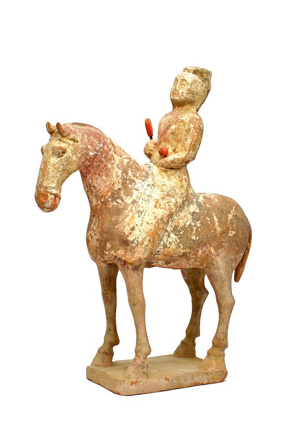 A Chinese pottery model of a horse and rider, Tang Dynasty , the rider seated upright holding drumsticks picked out in red, 33cm. high, cased.Together