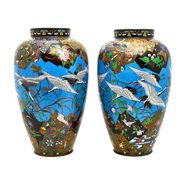 A pair of Japanese cloisonné vases, Meiji period, of slender ovoid form, each worked with a blue-ground central frieze depicting birds in flight above