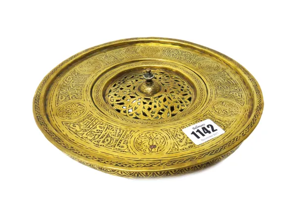 An Islamic brass bowl and cover, circa 1900, the compressed bowl and wide rim engraved with panels of script, the cover pierced with foliate designs,
