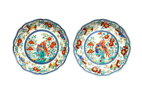 A pair of small Japanese Kakiemon dishes, Edo period, with foliate rims, each painted in the centre with two ho-o birds perched on rockwork beside peo
