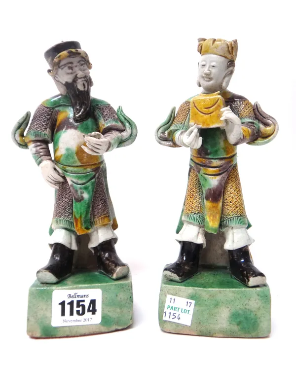 A pair of Chinese biscuit figures, 18th/19th century, each modelled as a man standing, one carrying a parcel, coloured in brown, aubergine, green and