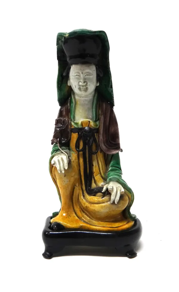 A Chinese biscuit figure of Guanyin, Kangxi, the goddess kneeling with her right hand resting on her knee and holding a lotus flower, coloured in aube