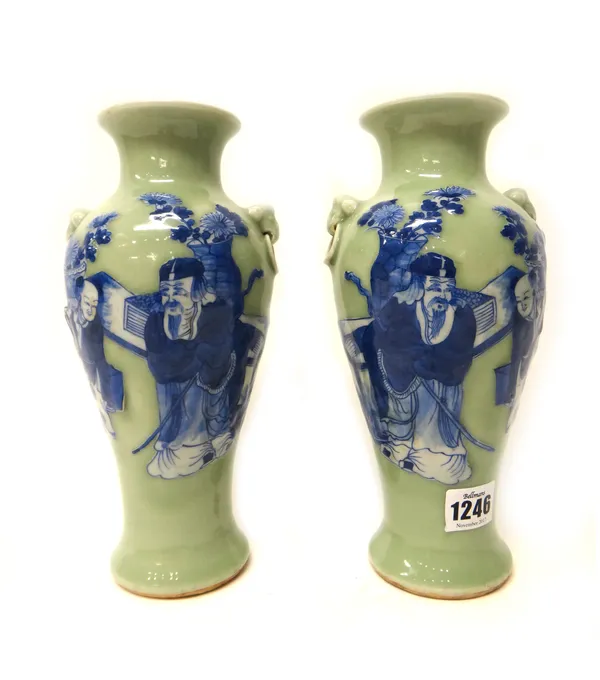 A pair of Chinese porcelain celadon-ground slender baluster vases, circa 1900, each painted in blue with a scholar and attendant, set with lion mask a
