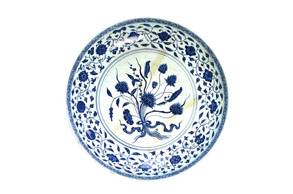 A large Chinese blue and white dish in Ming style, probably 18th century,  painted in the centre with a tied lotus bouquet, beneath a border of flower